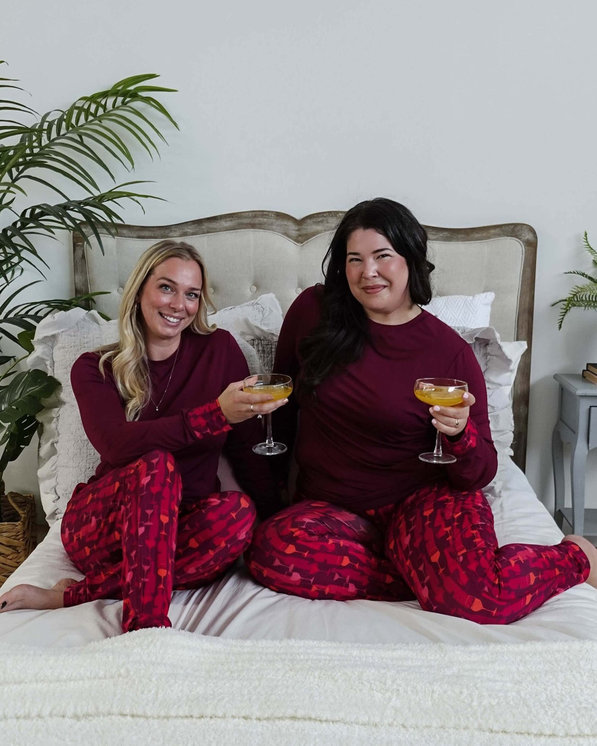 Vino Dreams PJ Long Sleeve Jogger Bamboo Set | GEORGIA RYLAN for women - two models cheers on a bed wearing the wine inspired set