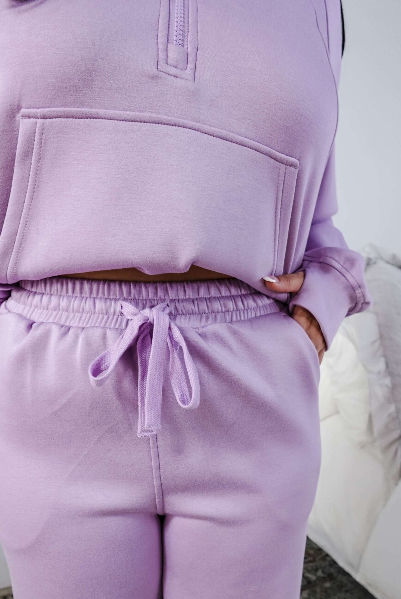 Person wearing a matching lavender hoodie and jogger set with a neutral background.