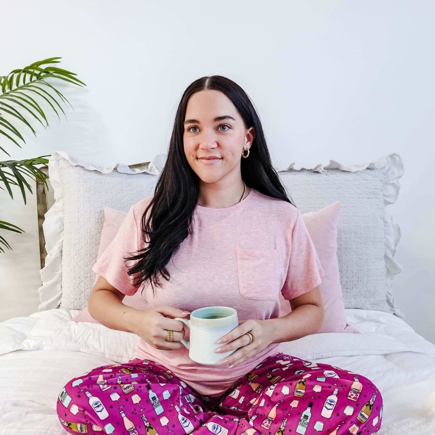 Sydney wearing the Wine Down velvety velour pajama set featuring hot pink wine print pants and a light pink pocket tee.