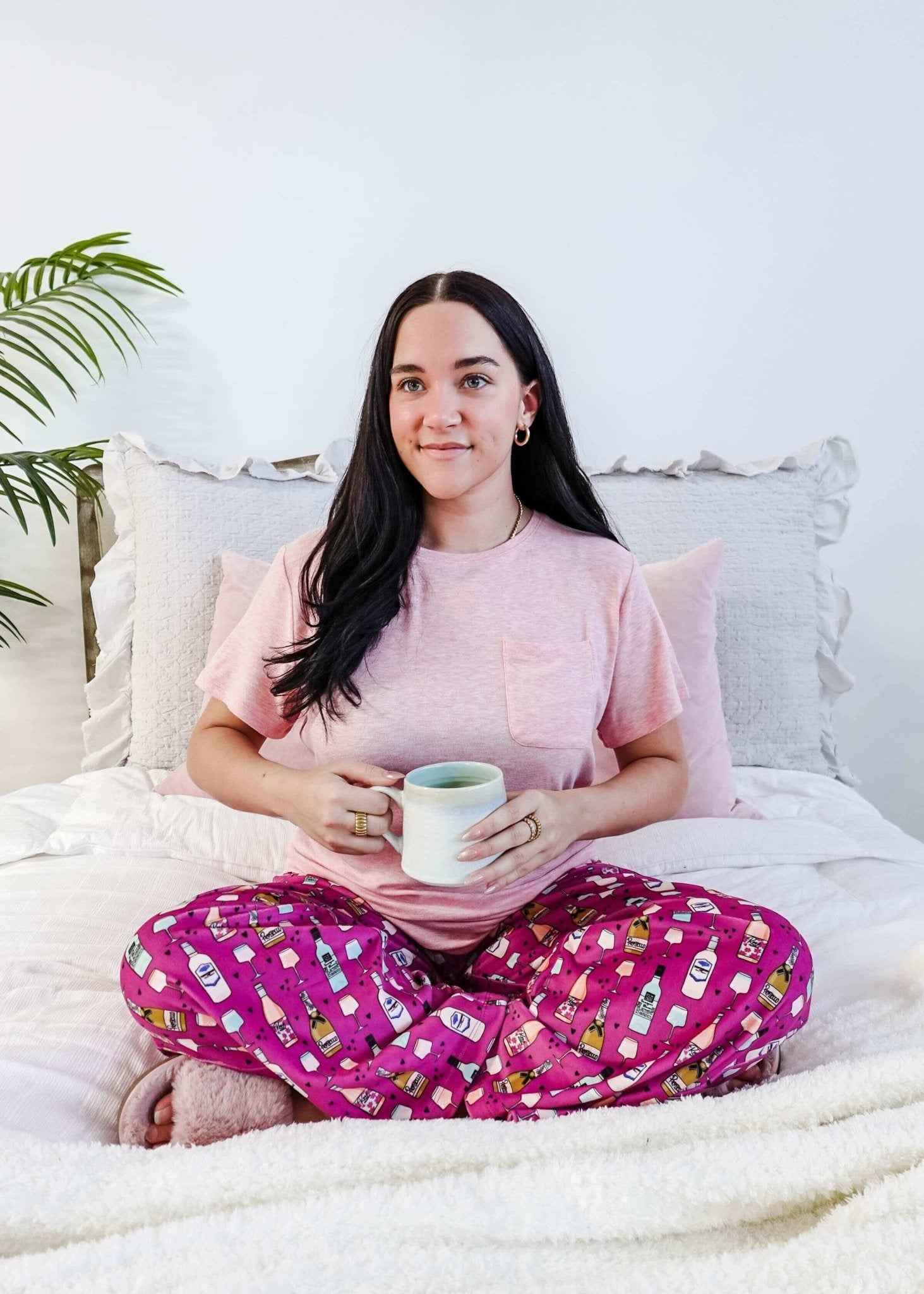 Sydney wearing the Wine Down velvety velour pajama set featuring hot pink wine print pants and a light pink pocket tee.