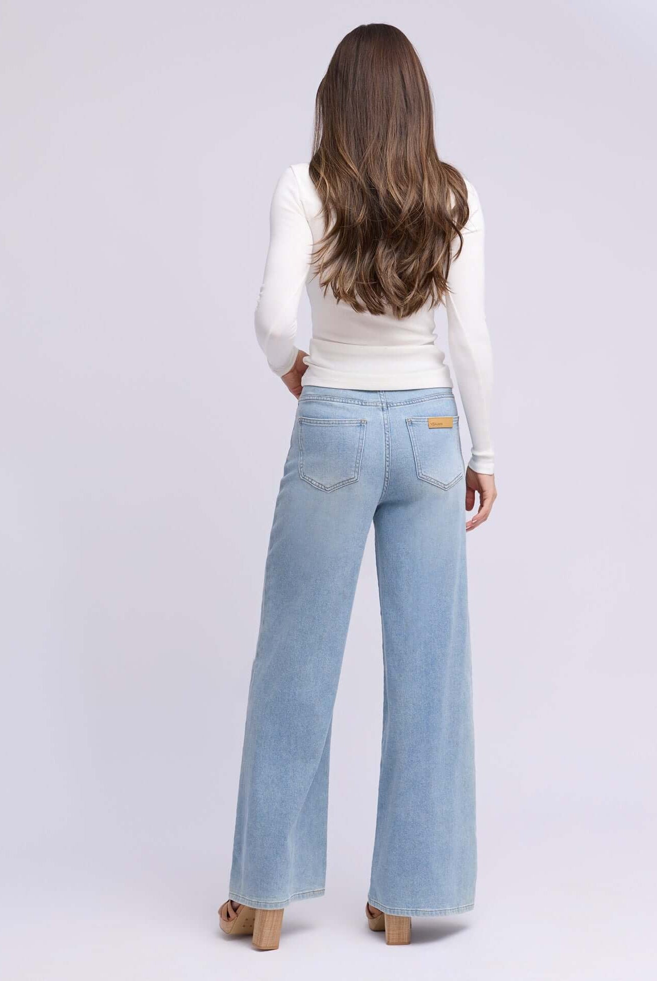 Woman wearing Yoga Jeans LILY Wide Leg Drawstring Jeans, view from the back showcasing the light blue denim style.