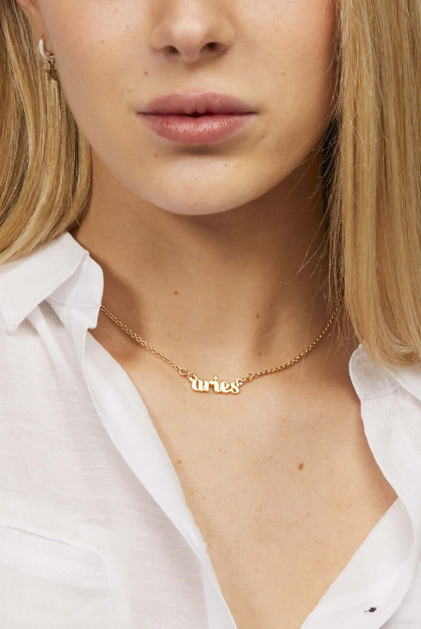 Zodiac Script Necklace in 14K Plated Gold featuring the Pisces astrological sign on a bright yellow display card.