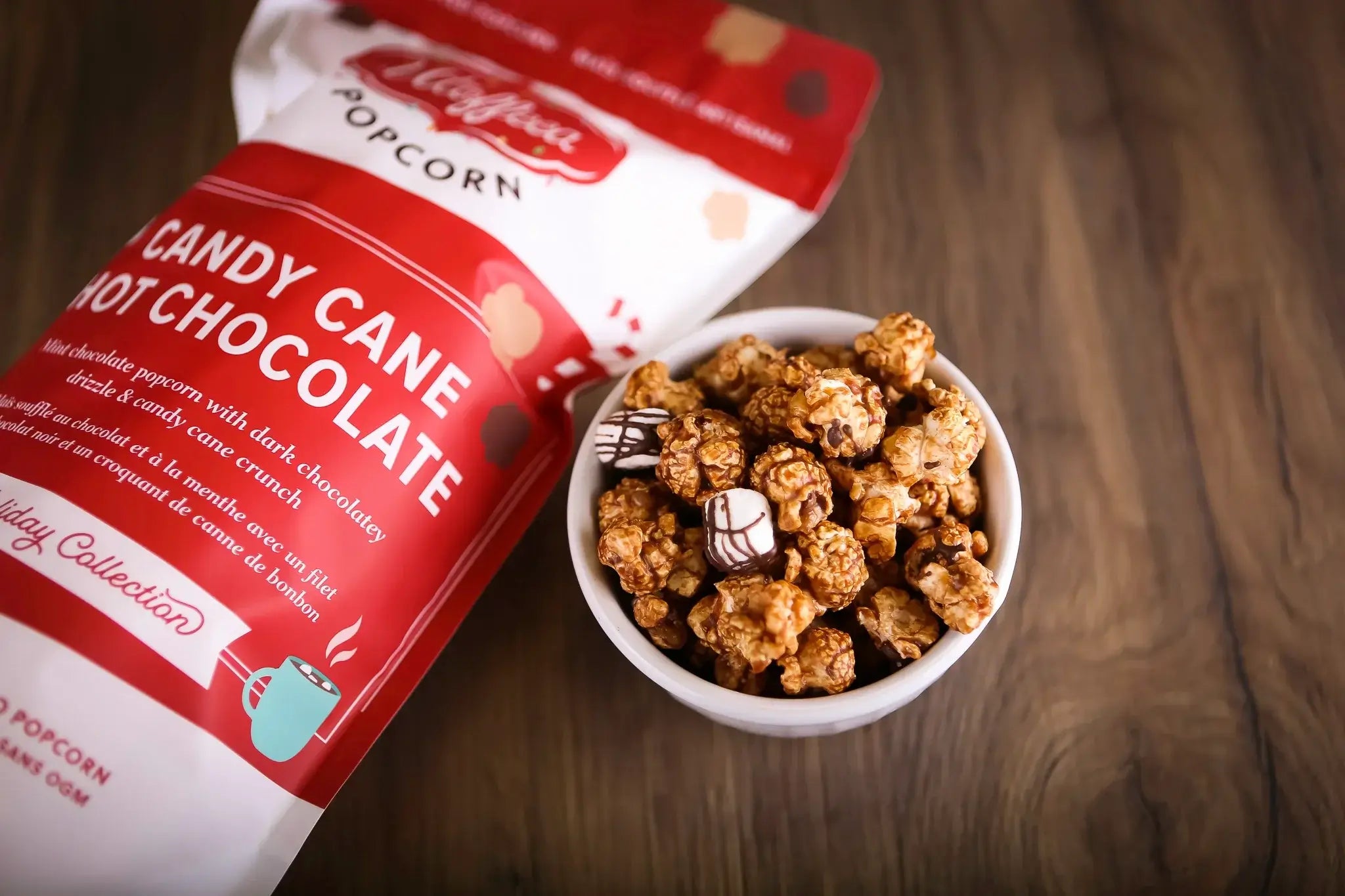 Candy Cane Hot Chocolate Handcrafted Popcorn Utoffeea in a bowl with a festive popcorn bag beside it.
