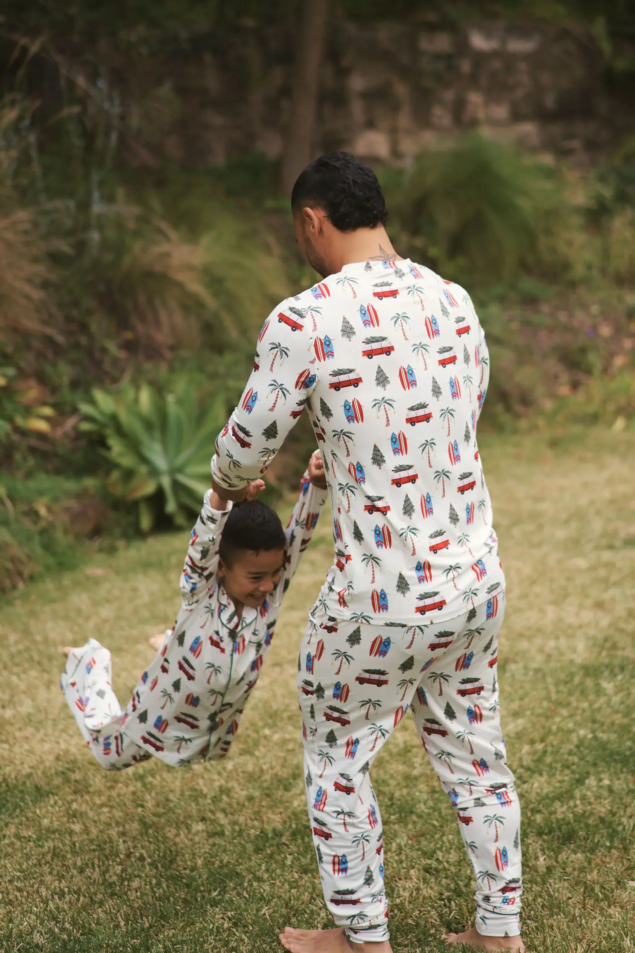 Father and child playing outdoors in Cali Beachy Christmas Men's Bamboo Henley Jogger Set with tropical patterns.