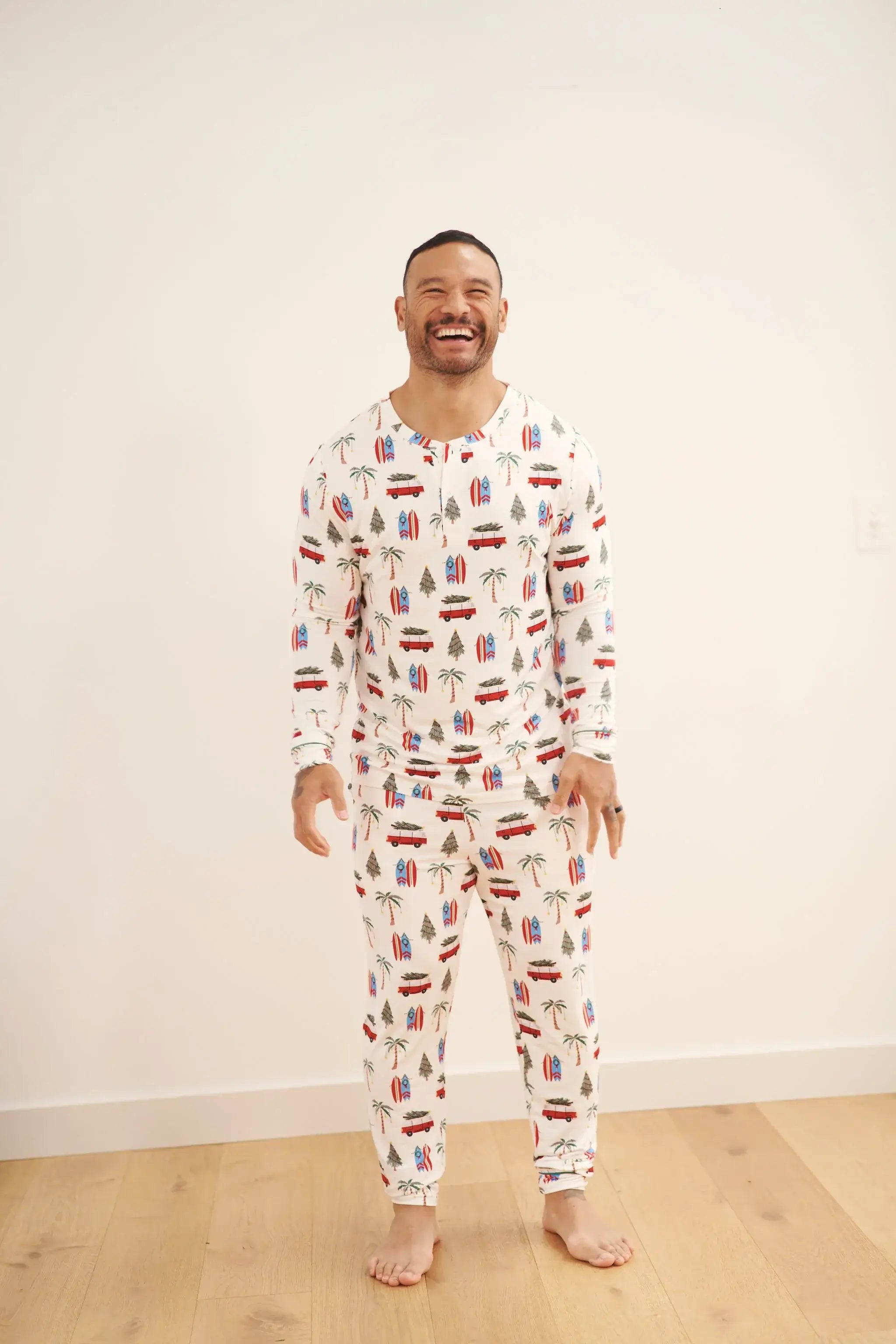 Smiling man wearing Cali Beachy Christmas Men's Bamboo Henley Jogger Set with tropical designs.