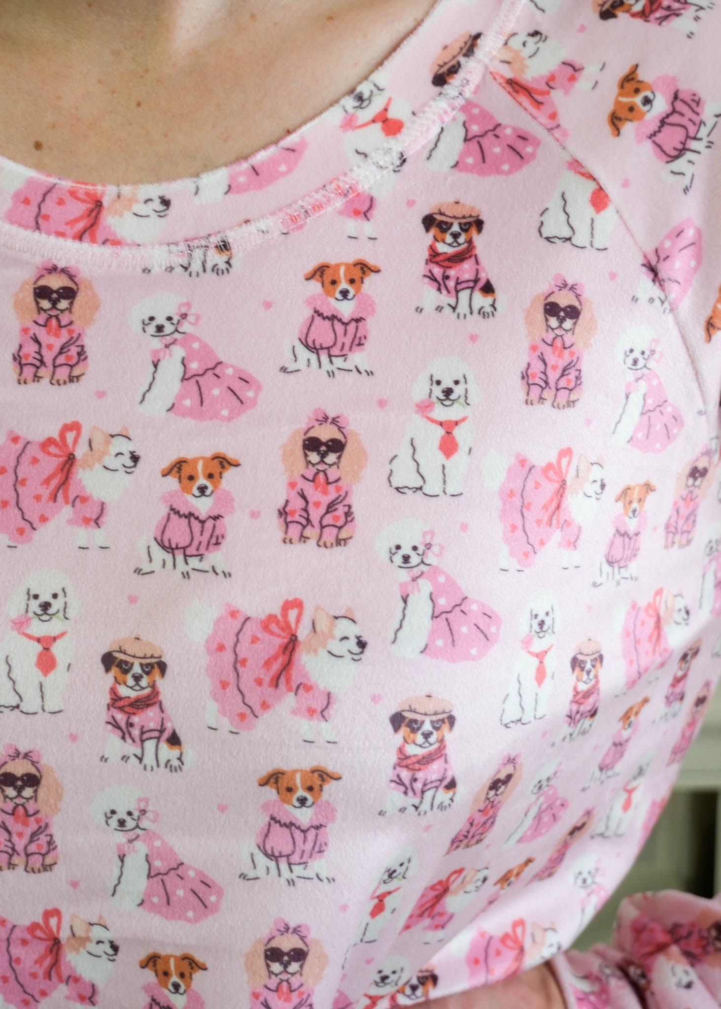Close up of person wearing Miranda Nic women's pink velour long sleeve top and jogger pants loungewear set featuring Chic Puppies dog print showing print and texture