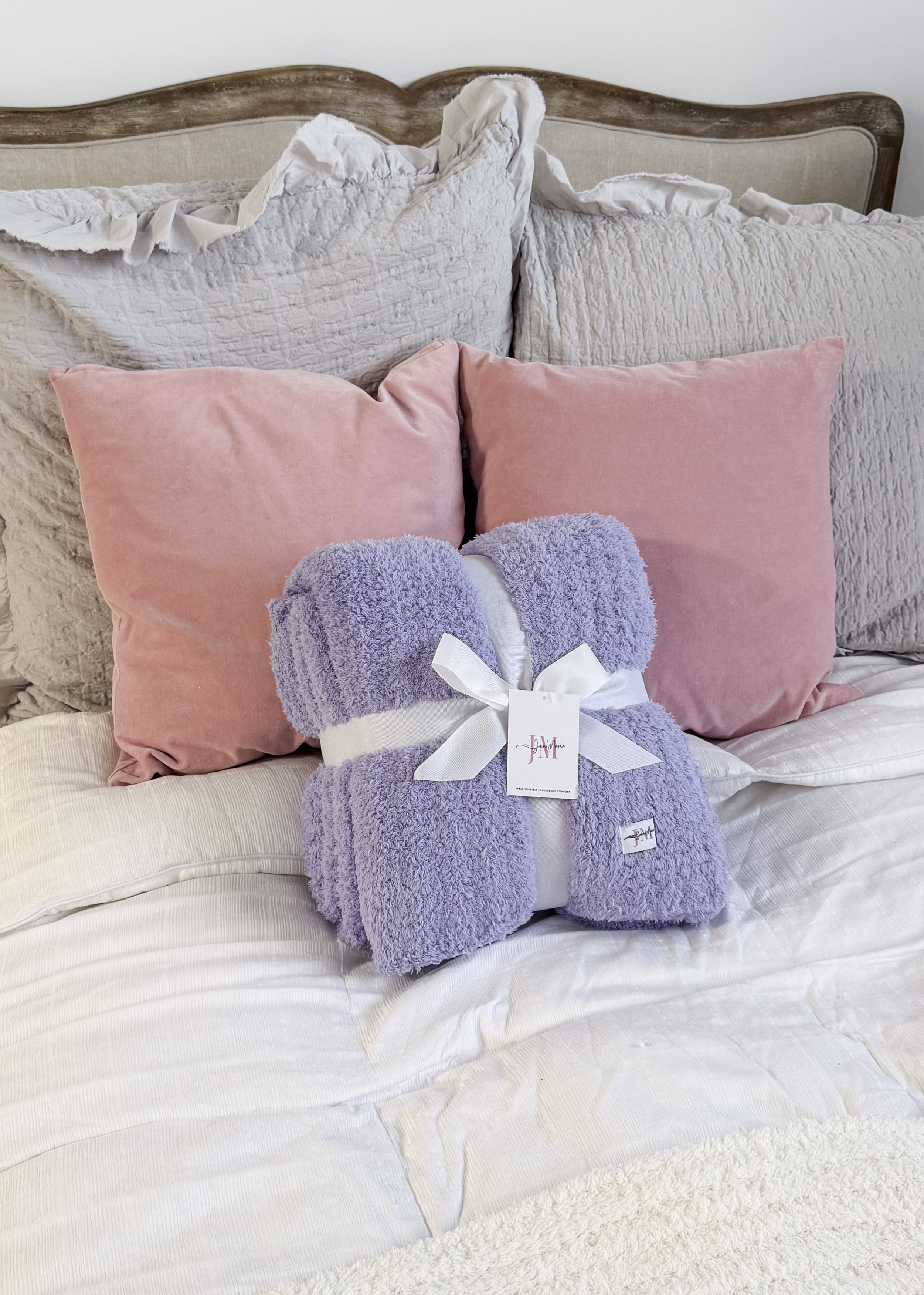 Lavender Purple Plush Cozy Cabin Blanket by Jan Marie - Purple blanket with a white tag on a bed with pink and gray pillows.