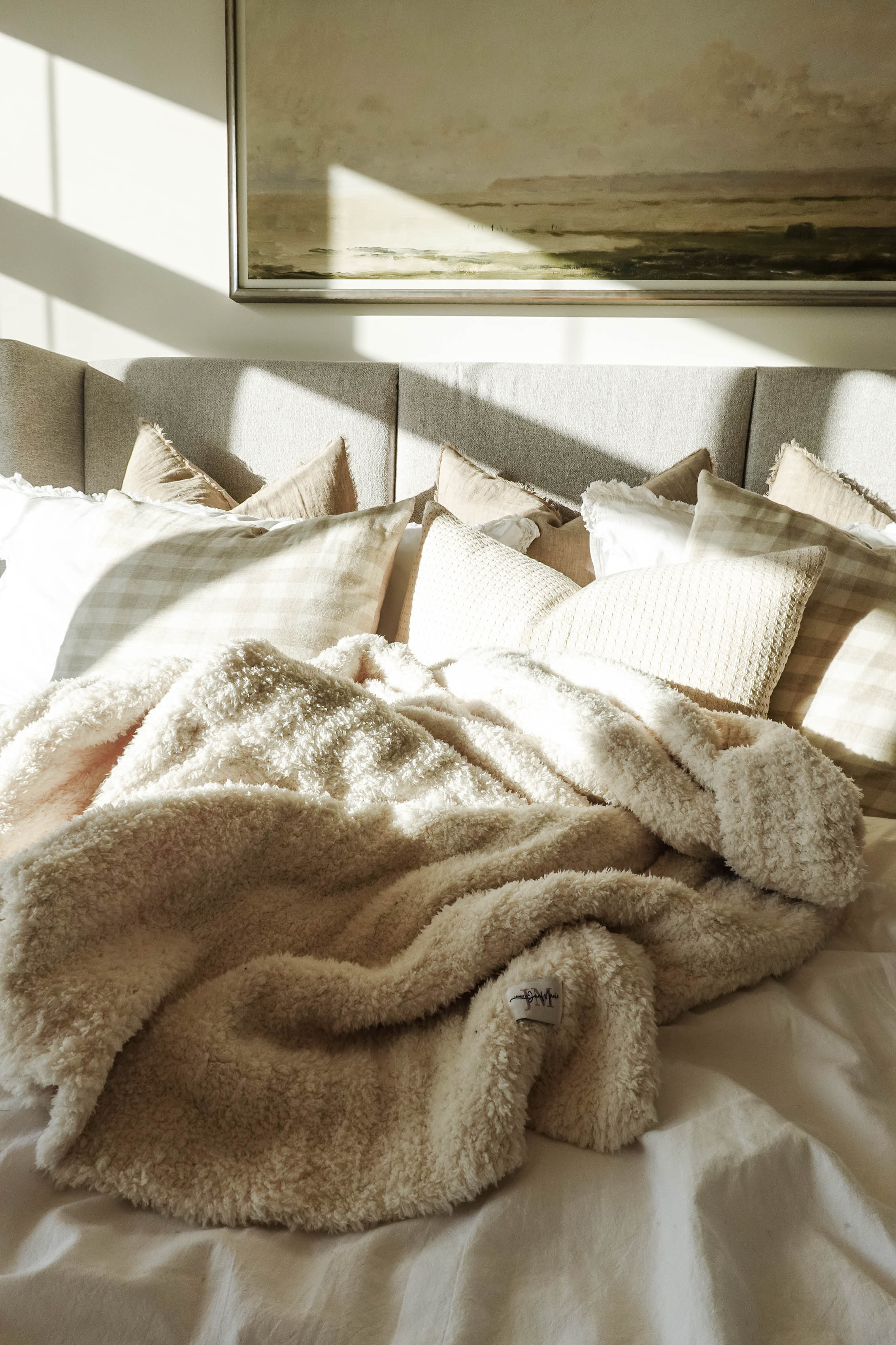 Cozy Cabin Blanket – Oversized Ivory Plush Throw (75″ × 52″) - shown in a beautiful neutral bedroom setting, haphazardly strewn on the bed to show the large size and texture. 