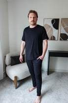 Black Unisex Short Sleeve Tee Bamboo showcased on a model standing in a modern interior setting.