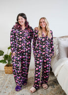 Georgia Rylan women's bamboo long sleeve button-up top and straight-leg pajama pants in Dreamy Blooms black floral print - Cloud Nine Pajamas on models in a bedroom setting