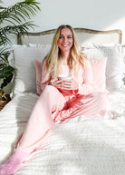 woman on bed wearing heather pink top straight pant lounge set