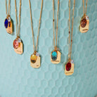 all-groups Birthstone Charm Necklace in 14k Plated Gold with oval-cut stones and intention words displayed on a blue background.