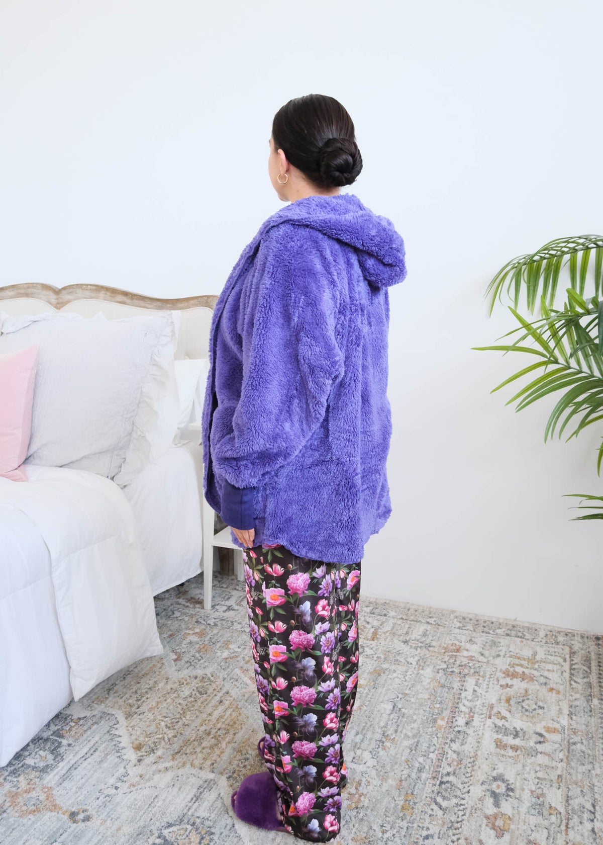 Close-up detail of the Jan Marie Fluffy hooded cardigan's deep front pocket in purple plush fabric, with a hand tucked inside and the purple ribbed cuff visible, floral pajama pants underneath. Cloud Nine Pajamas Edmonton