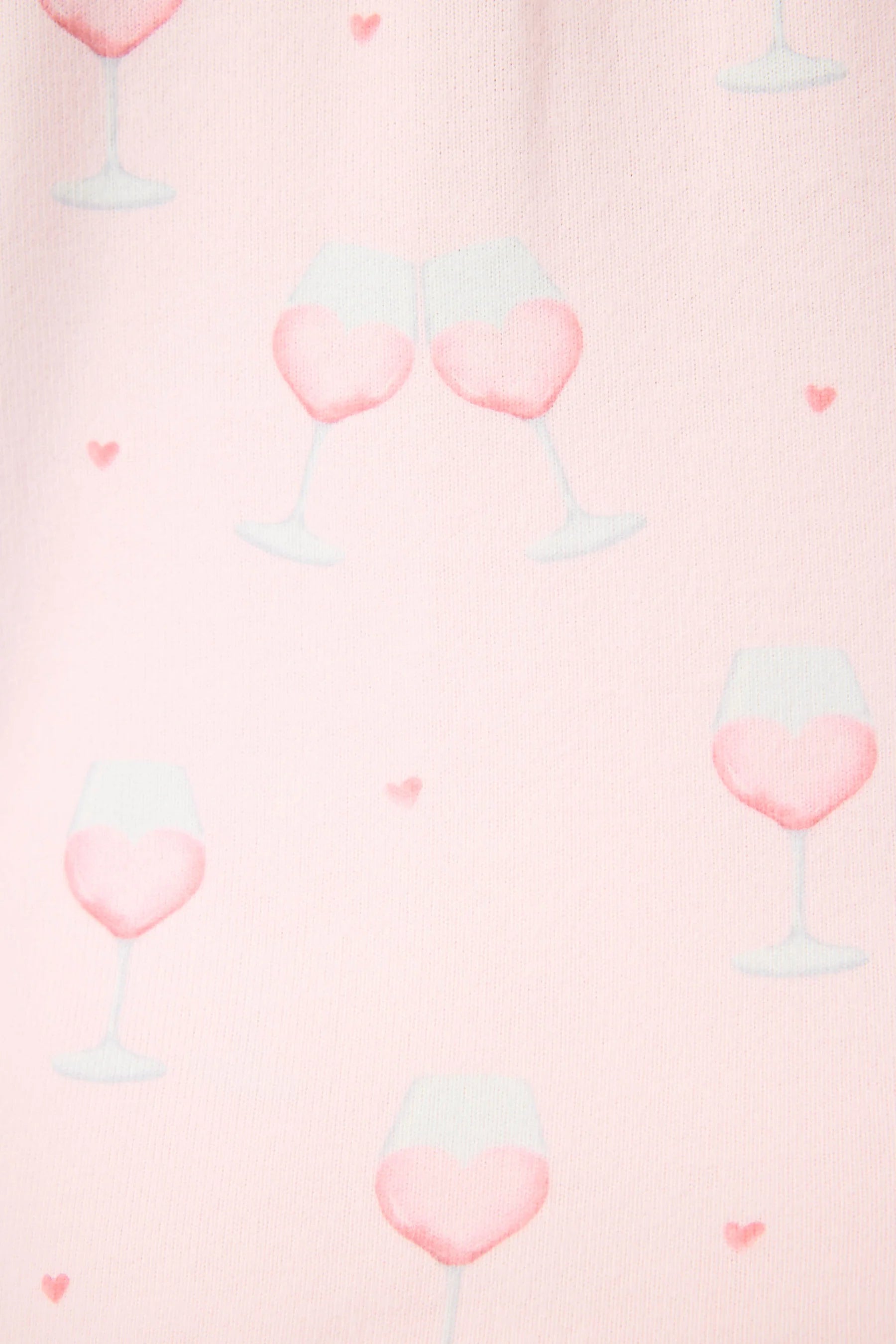 Happy Hour Wine Glass Print 3-Piece PJ Set | PJ Salvage women's wine glass print pj set in pink - button up long sleeve top, straight leg pants, and matching eye mask close up of the pink wine print, the "wine" looks like a heart and there are small hearts around the glass. 