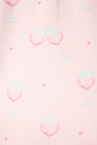 Happy Hour Wine Glass Print 3-Piece PJ Set | PJ Salvage women's wine glass print pj set in pink - button up long sleeve top, straight leg pants, and matching eye mask close up of the pink wine print, the "wine" looks like a heart and there are small hearts around the glass. 