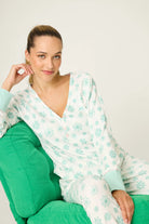 Model (Alexis, 5'8") wearing the PJ Salvage Snowflake Wishes Pointelle PJ Set, showing the ivory V-neck henley top with striped cuffs and jogger pants with a pink tie in the green snowflake print.