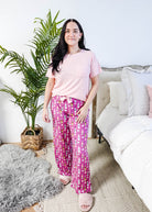 Sydney wearing the Wine Down velvety velour pajama set featuring hot pink wine print pants and a light pink pocket tee.
