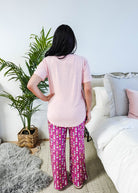 Sydney wearing the Wine Down velvety velour pajama set featuring hot pink wine print pants and a light pink pocket tee.
 showing back view