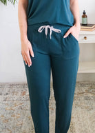 A person wearing dark teal pants with a grey ribbon drawstring and side pockets, the person is wearing the Pj Tee Jogger Midnight Teal Bamboo Pj Set. Cloud Nine Pajamas Edmonton