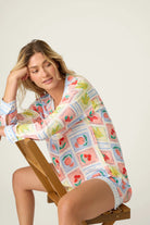 Frutta Fresca Summer Harvest Button Up Top & Short Set PJ Salvage model sitting on a chair, showcasing colorful fruit print.
