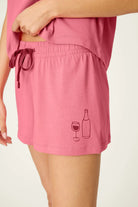 PJ SALVAGE Graphic Print Softee Tee & Short Lounge Set in "Time to Wine Down" rose pink. Model stands against a light background in a close-up shot of the short length and detail