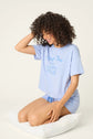 PJ SALVAGE Graphic Print Softee Tee & Short Lounge Set in "Nap Time is my Happy Hour" graphic tee shirt in light blue. Model sits against a light background in a close-up lifestyle shot