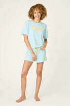 PJ SALVAGE Graphic Print Softee Tee & Short Lounge Set in "Breakfast Club" graphic tee shirt in light blue. Model stands against a light background in a full length shot