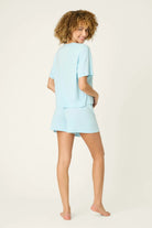 PJ SALVAGE Graphic Print Softee Tee & Short Lounge Set in "Breakfast Club" graphic tee shirt in light blue. Model stands against a light background in a back view profile shot