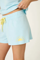 PJ SALVAGE Graphic Print Softee Tee & Short Lounge Set in "Breakfast Club" graphic tee shirt in light blue. Model stands against a light background in a close up of short profile shot