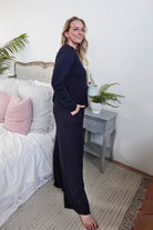 Model wearing Long Sleeve Raw Edge Straight Pant Lounge Set, standing beside a bed and decorative plants.