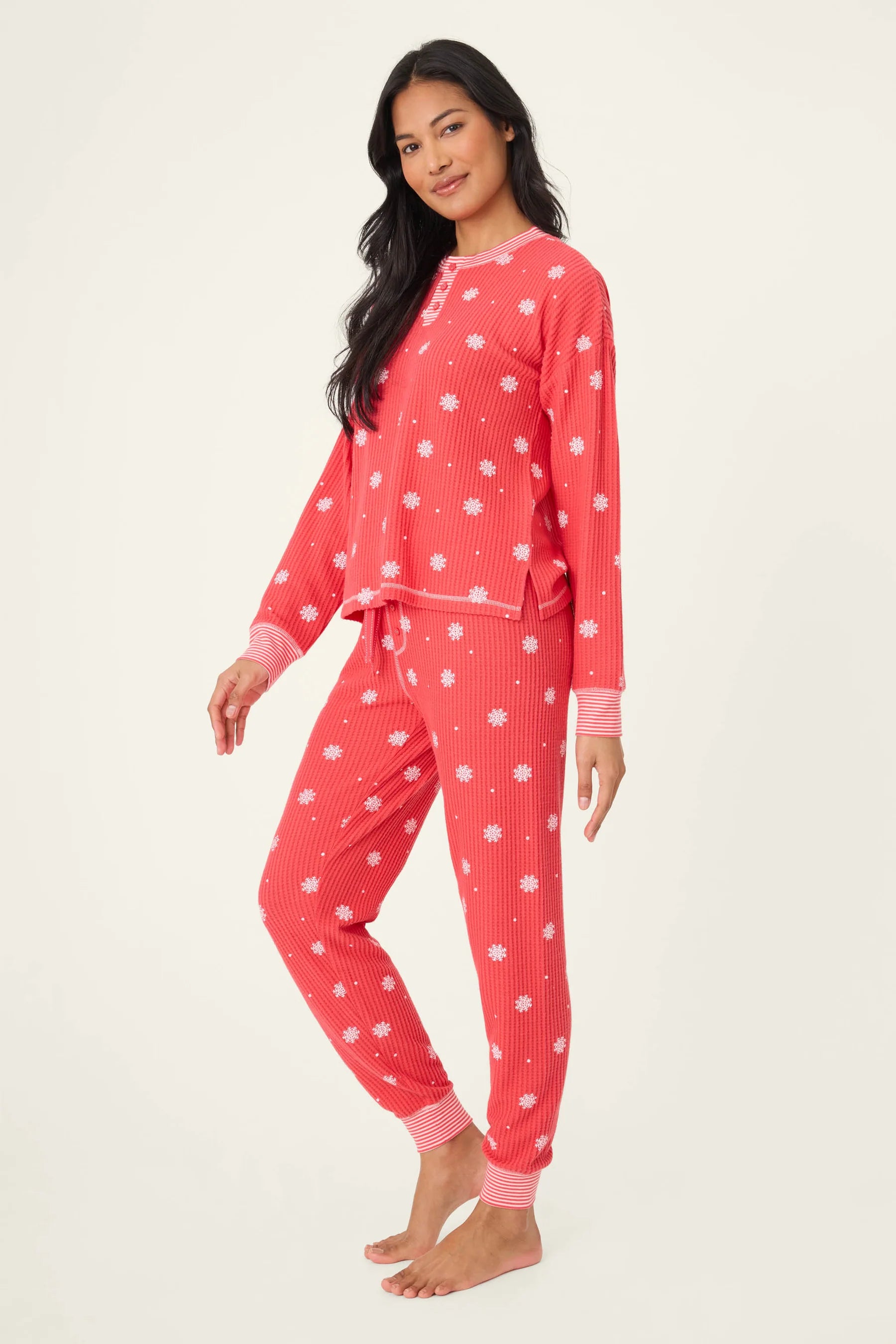  Woman wearing Ski Jammie Classics Brushed Thermal PJ Set, featuring playful winter prints in red and pink snowflake wishes