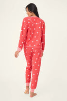  Woman wearing Ski Jammie Classics Brushed Thermal PJ Set, featuring playful winter prints in red and pink snowflake wishes