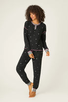  Woman wearing Ski Jammie Classics Brushed Thermal PJ Set, featuring playful winter prints in black starlight starbright star print