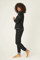  Woman wearing Ski Jammie Classics Brushed Thermal PJ Set, featuring playful winter prints in black starlight starbright star print