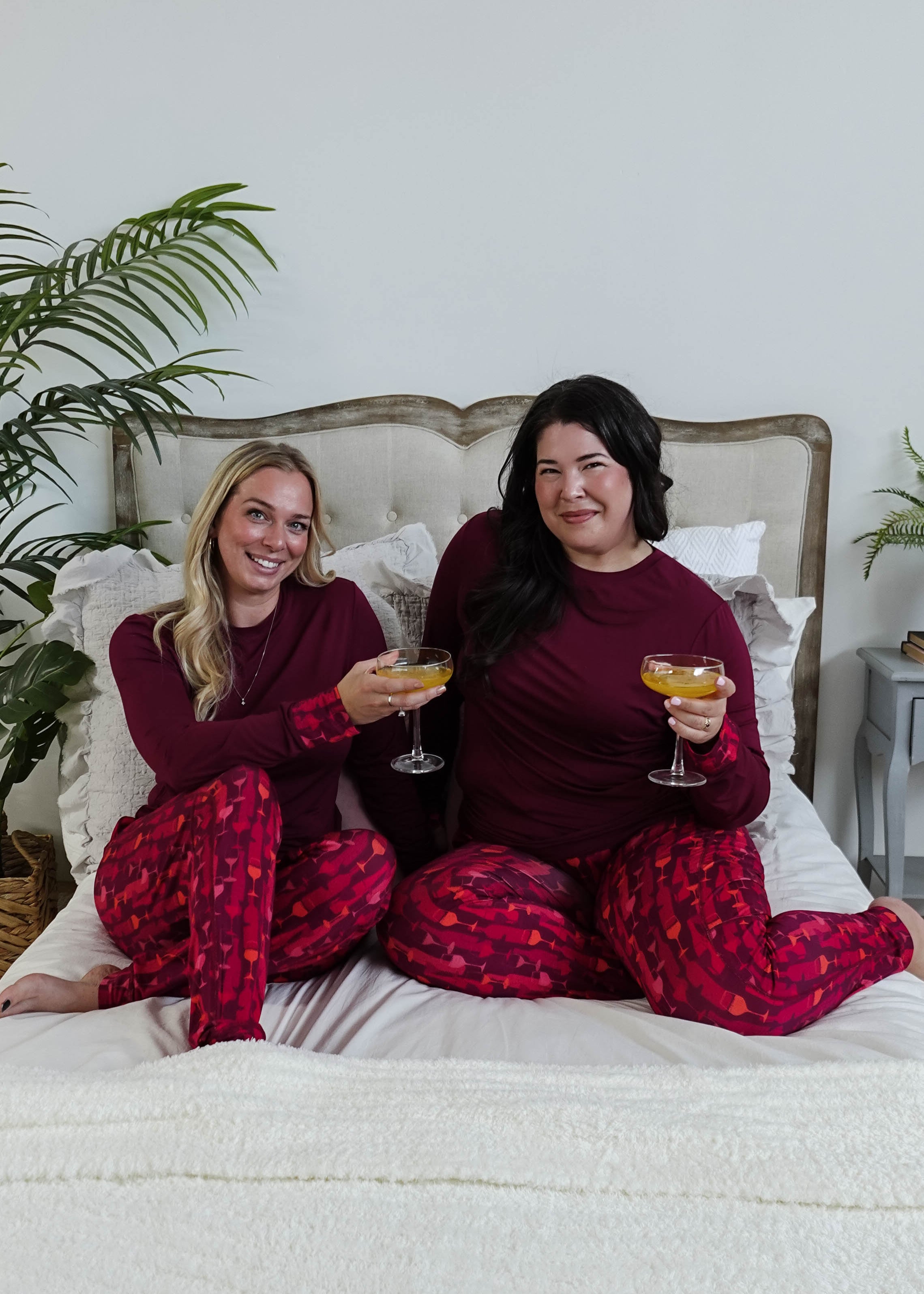 Vino Dreams PJ Long Sleeve Jogger Bamboo Set | GEORGIA RYLAN for women - two models cheers on a bed wearing the wine inspired set