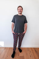 Man wearing Arcade After Dark Unisex Bamboo Jogger with graphic design, paired with a gray t-shirt, and socks.