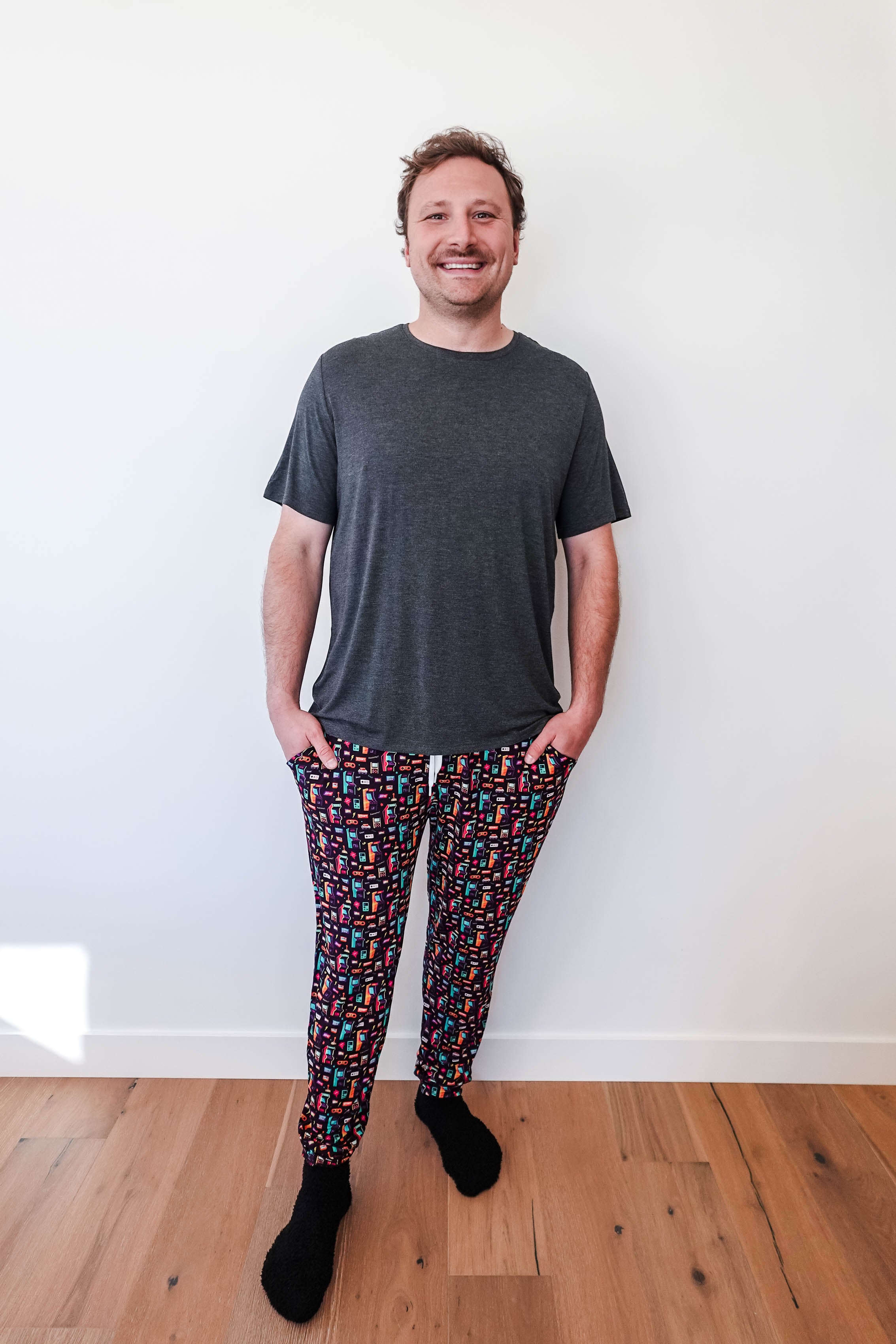 Man wearing Arcade After Dark Unisex Bamboo Jogger with graphic design, paired with a gray t-shirt, and socks.