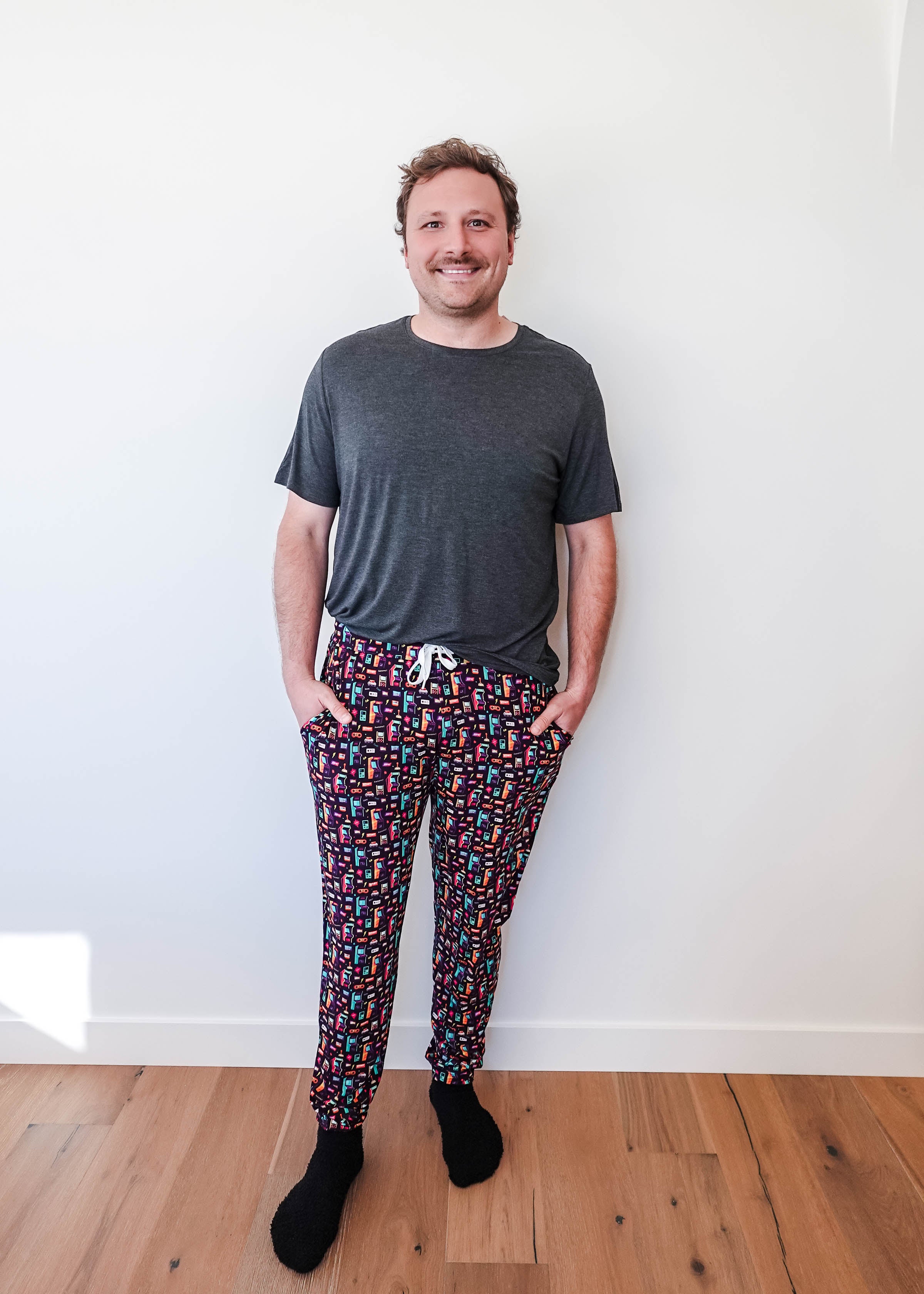 Man wearing Arcade After Dark Unisex Bamboo Jogger with graphic design, paired with a gray t-shirt, and socks.