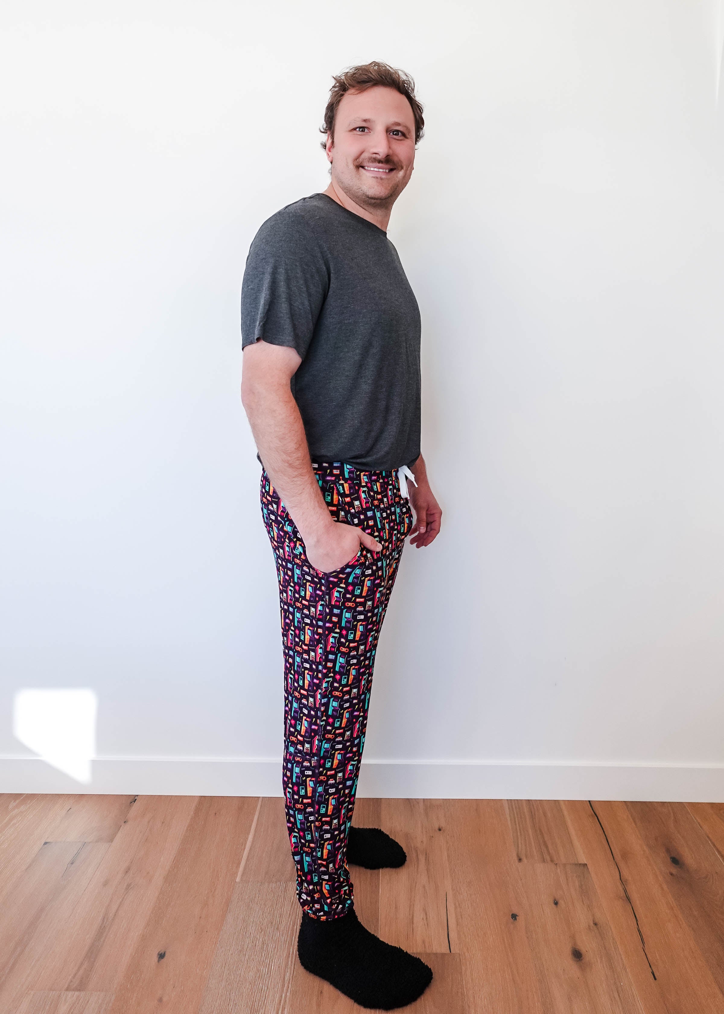 Man wearing Arcade After Dark Unisex Bamboo Jogger with graphic design, paired with a gray t-shirt, and socks.