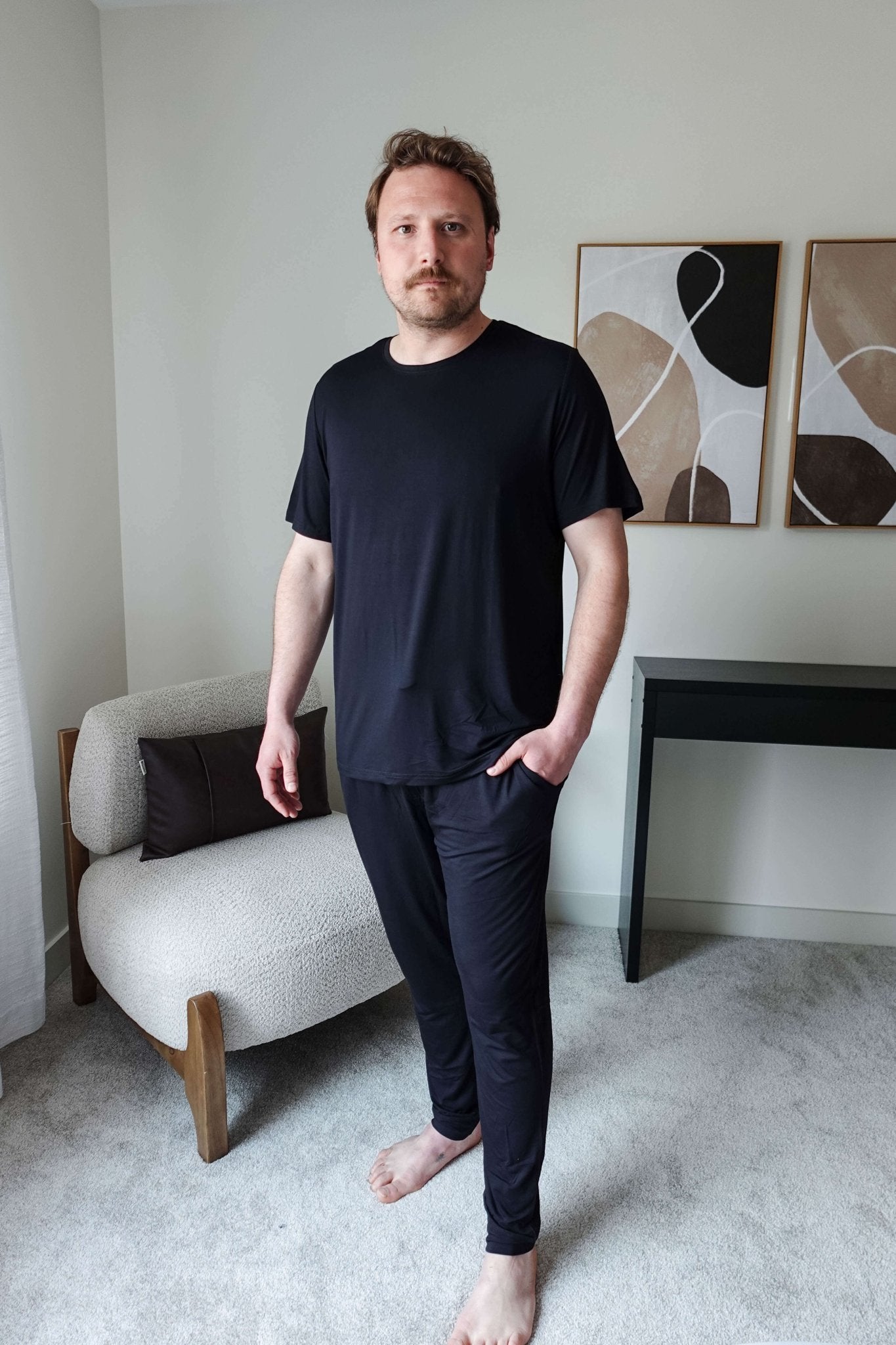 Black Unisex Short Sleeve Tee Bamboo showcased on a model standing in a modern interior setting.