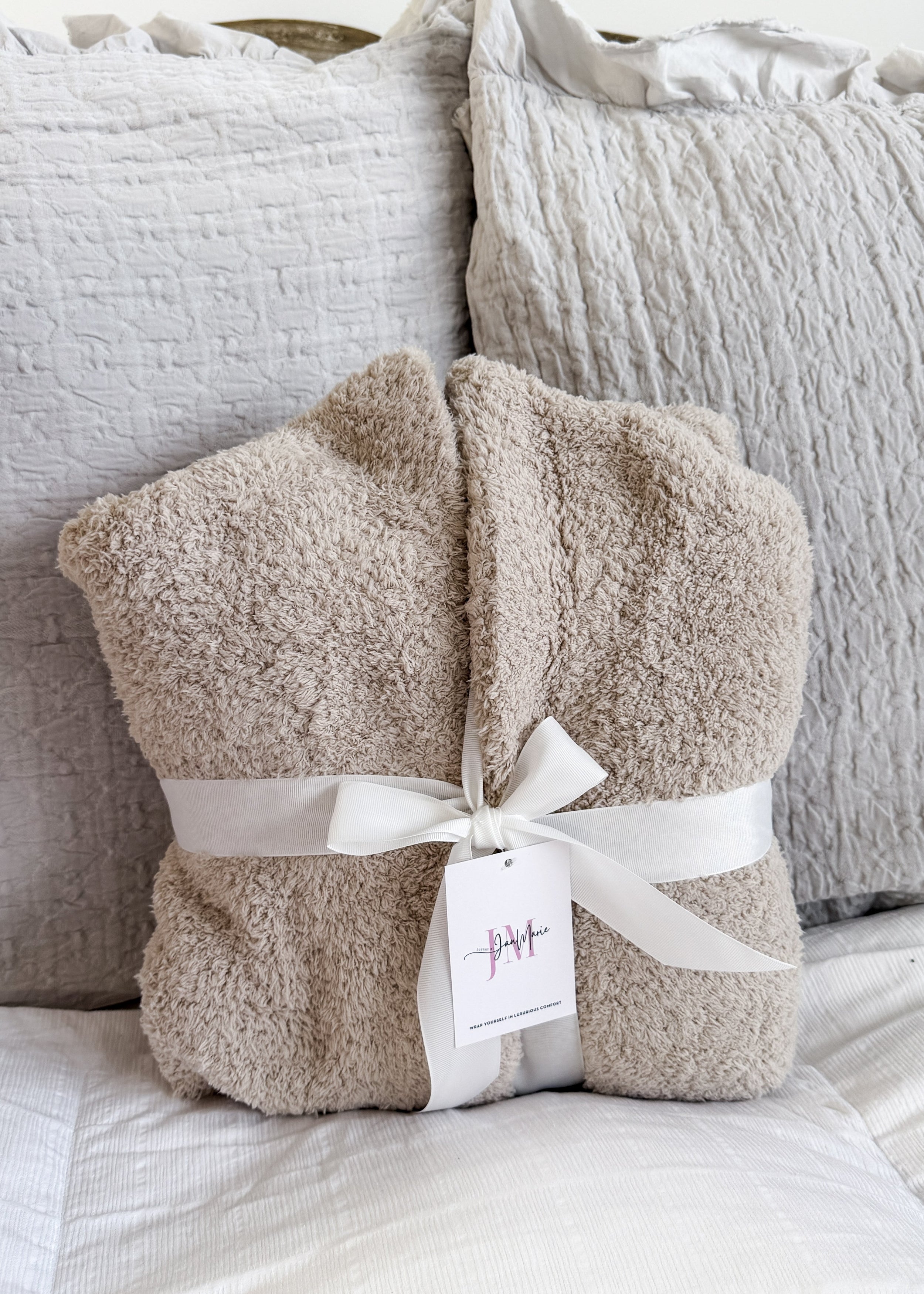 Sand Beige Chenille Cloud Spa Robe – Plush Stretch Robe with Pockets - showing robe folded in a square on the bed and wrapped in a fabric white wide ribbon, which is how it's sold making a great gift presentation