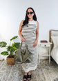 Woman wearing a black and white striped knit dress in a bedroom setting.