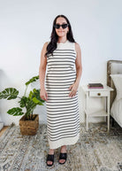 Woman wearing a black and white striped knit dress in a bedroom setting.