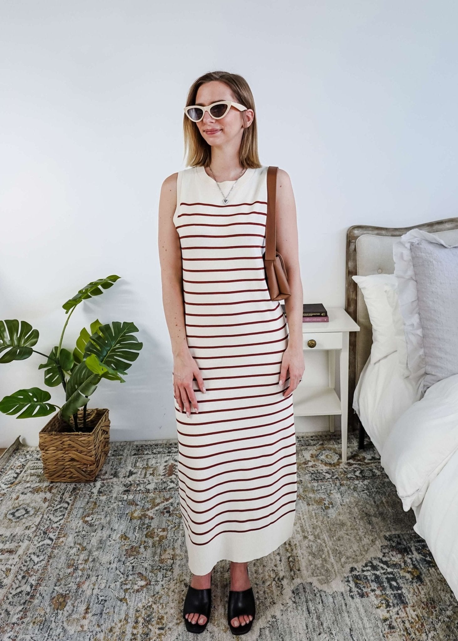 Woman wearing a brown and white striped knit dress in a bedroom setting.