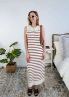 Woman wearing a brown and white striped knit dress in a bedroom setting.