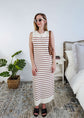Woman wearing a brown and white striped knit dress in a bedroom setting.