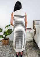 Woman wearing a black and white striped dress in a bedroom setting.