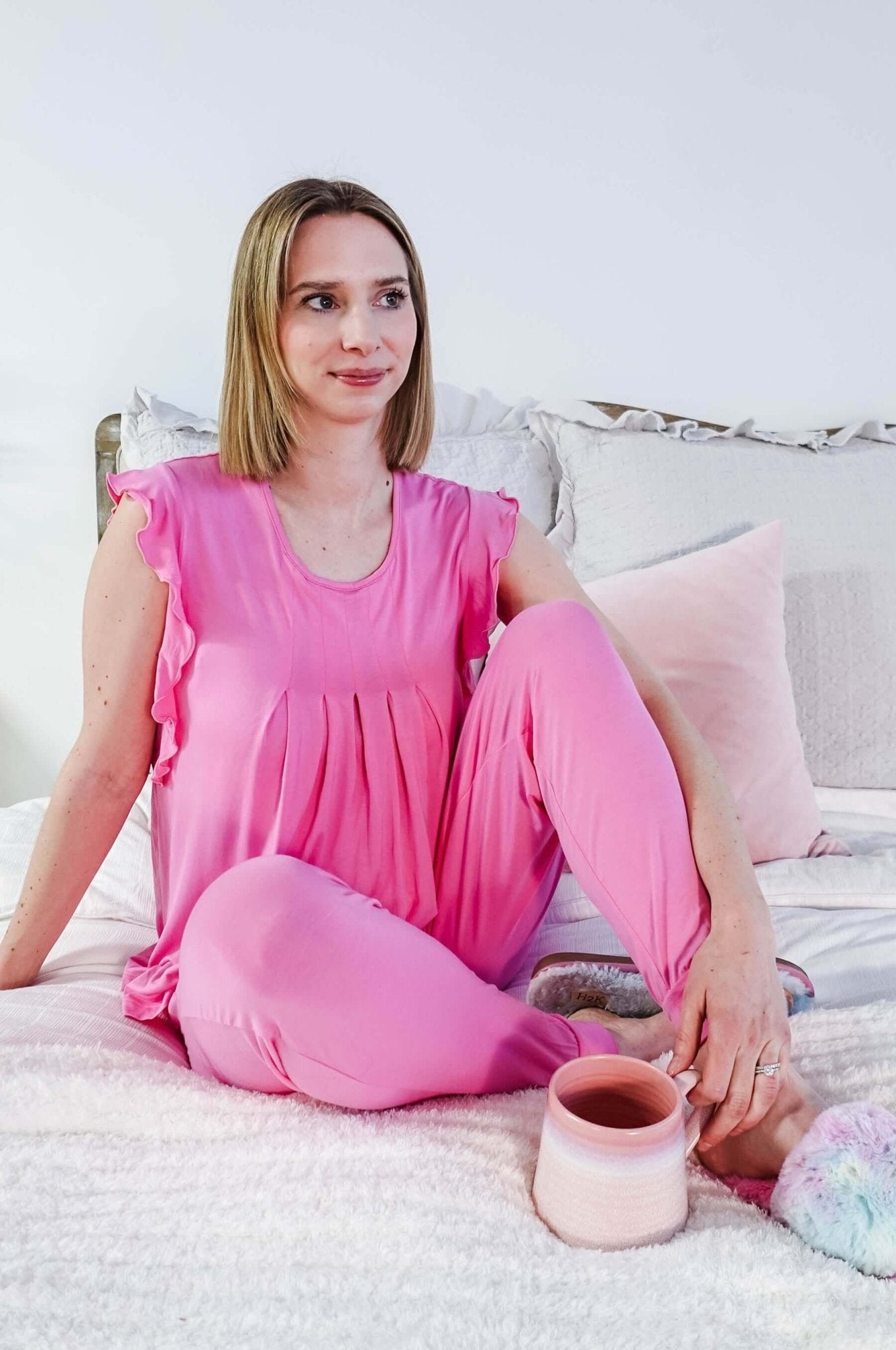 Bubblegum Pink Flutter Top and Jogger Bamboo PJ Lounge Set worn by a woman sitting on a bed, relaxed and comfortable.