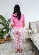 Back view of a model wearing the Dream In Blooms Tee & Jogger Bamboo Lounge Set in bubblegum pink with floral joggers.