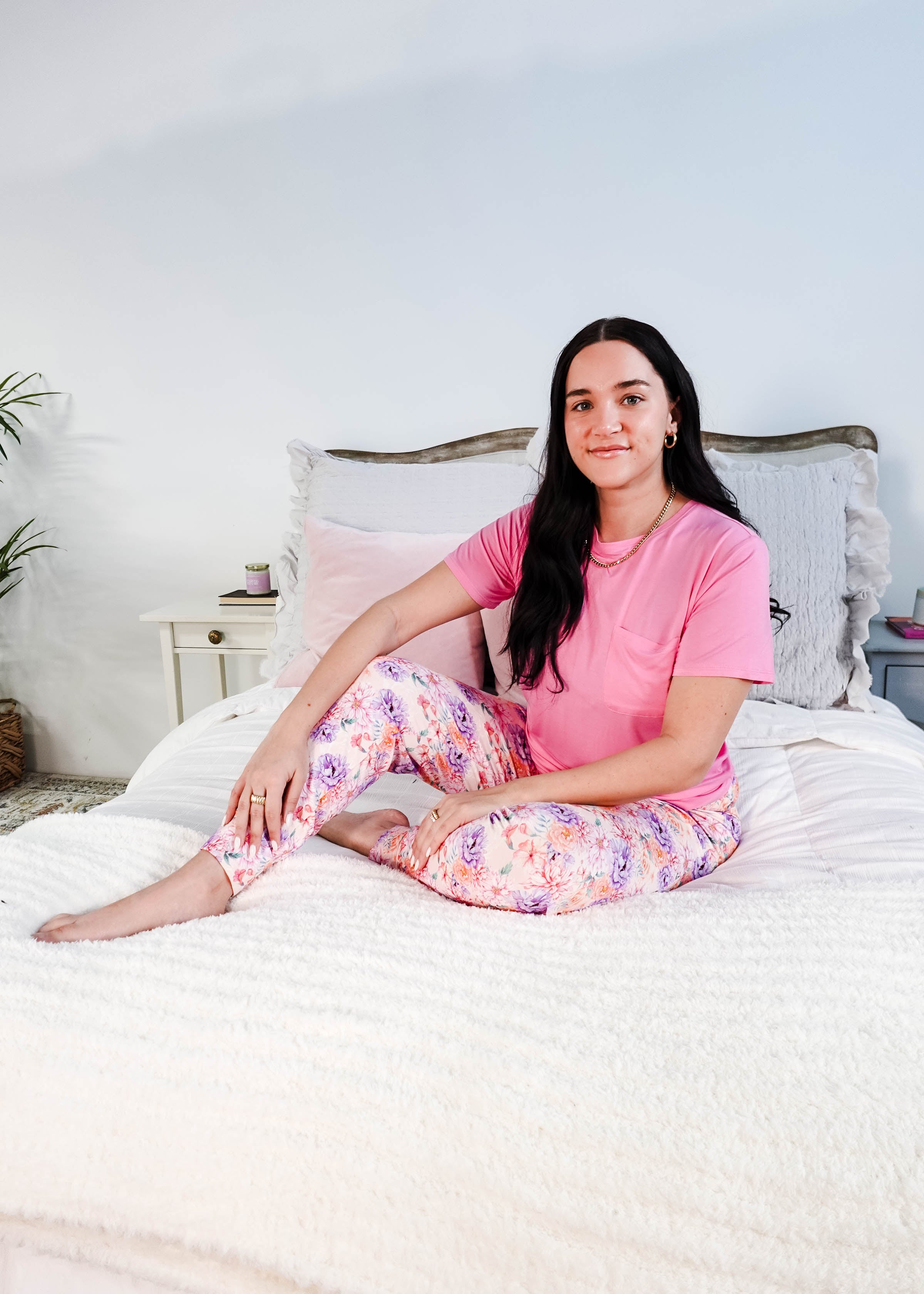 Model wearing the Dream In Blooms Tee & Jogger Bamboo Lounge Set on a bed with floral joggers.